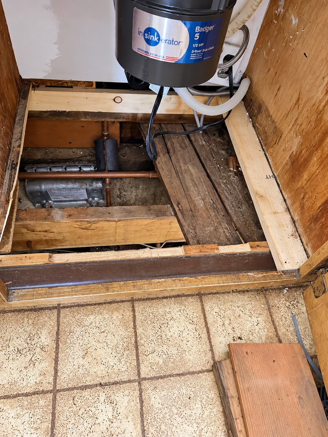 Opened cabinet base showing the supporting wood and plumbing