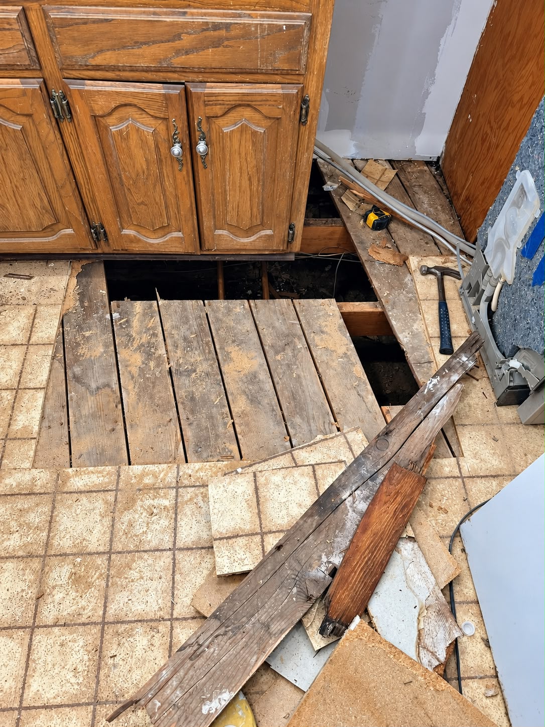 Kitchen subfloor opened beside the cabinets with removed boards