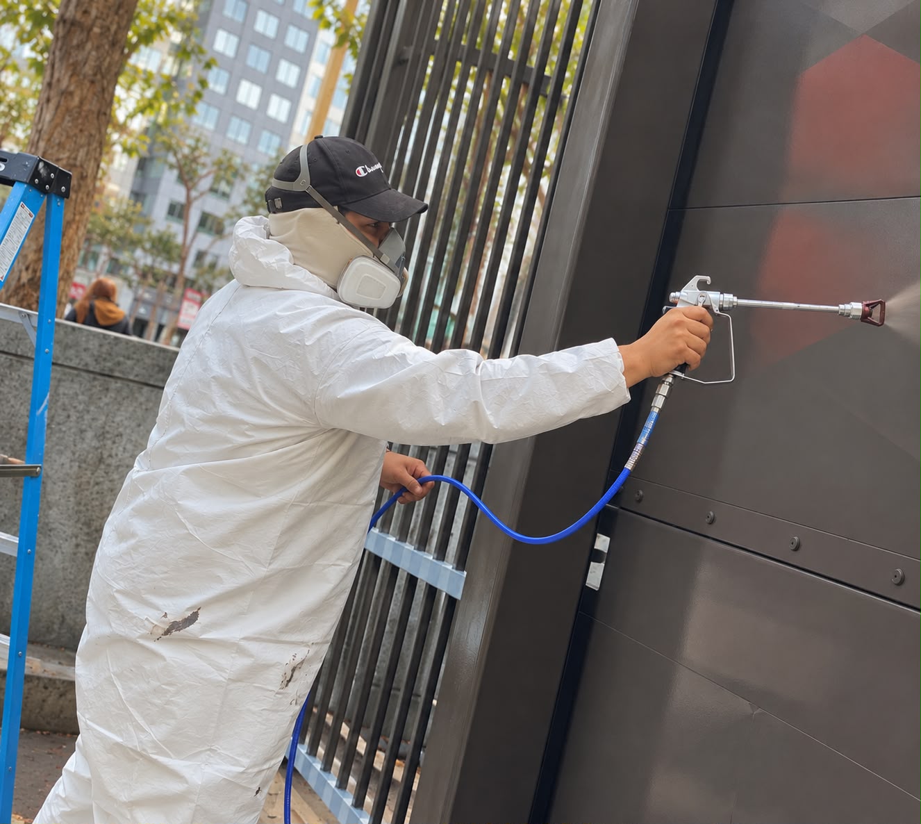 Rodrigo working on a construction project, applying a finish with a spray gun