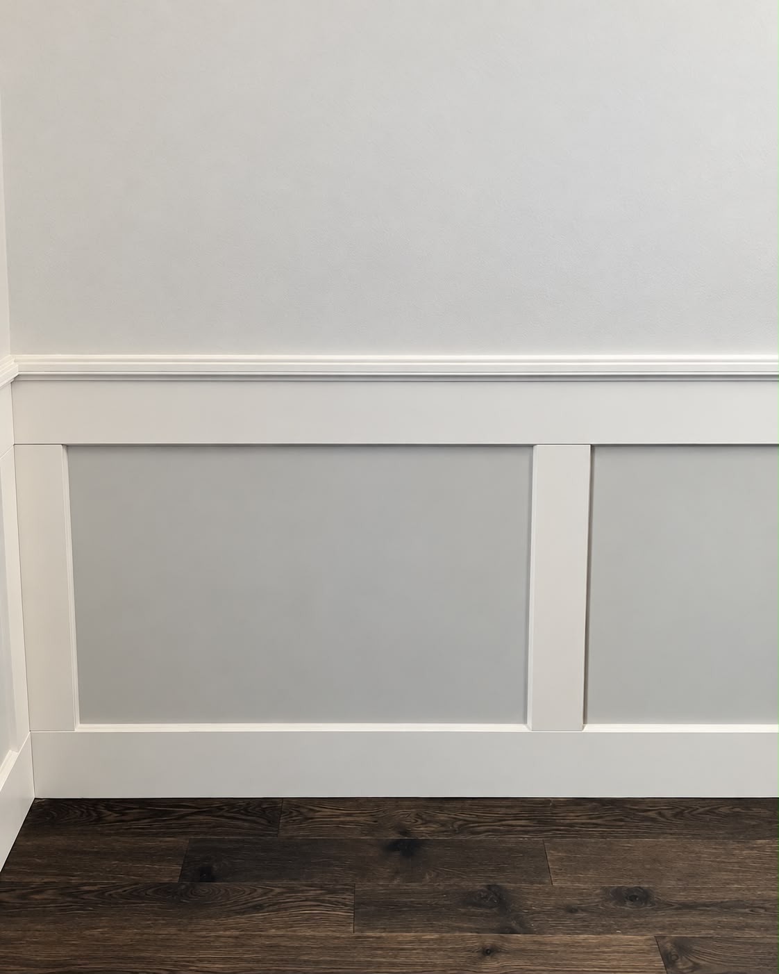 Close view of crisp white panel molding, chair rail, and baseboard installation